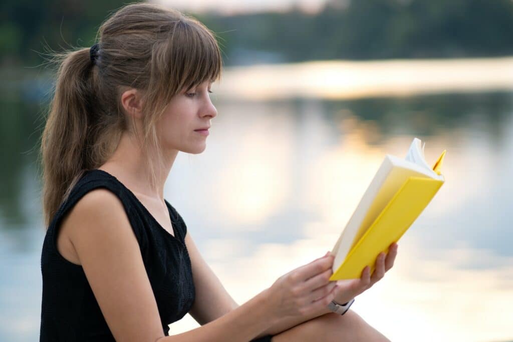 Young woman resting in summer park reading a book. Education and sudy concept